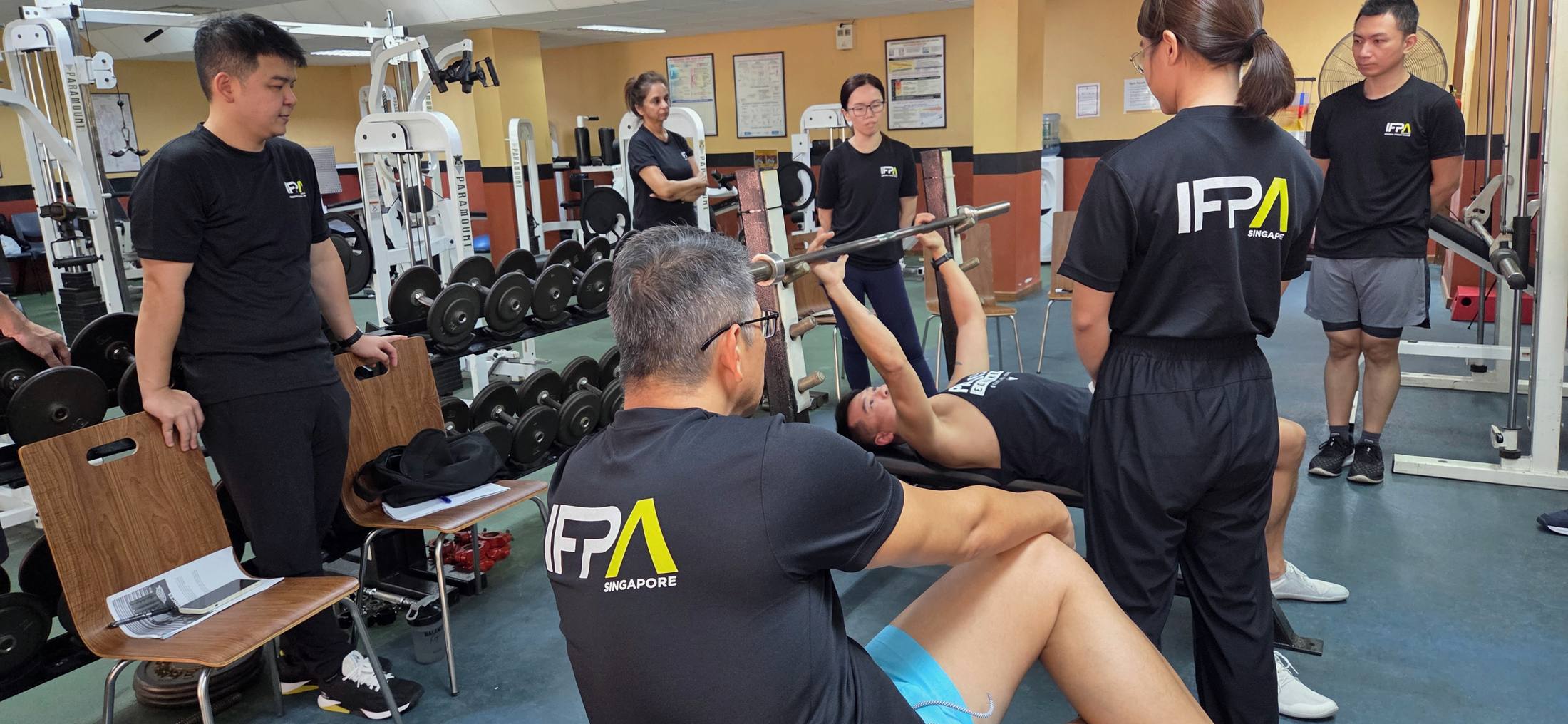 A bench press coaching demonstration during an IFPA PFT practical day